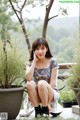 A woman sitting on a chair next to a potted plant.