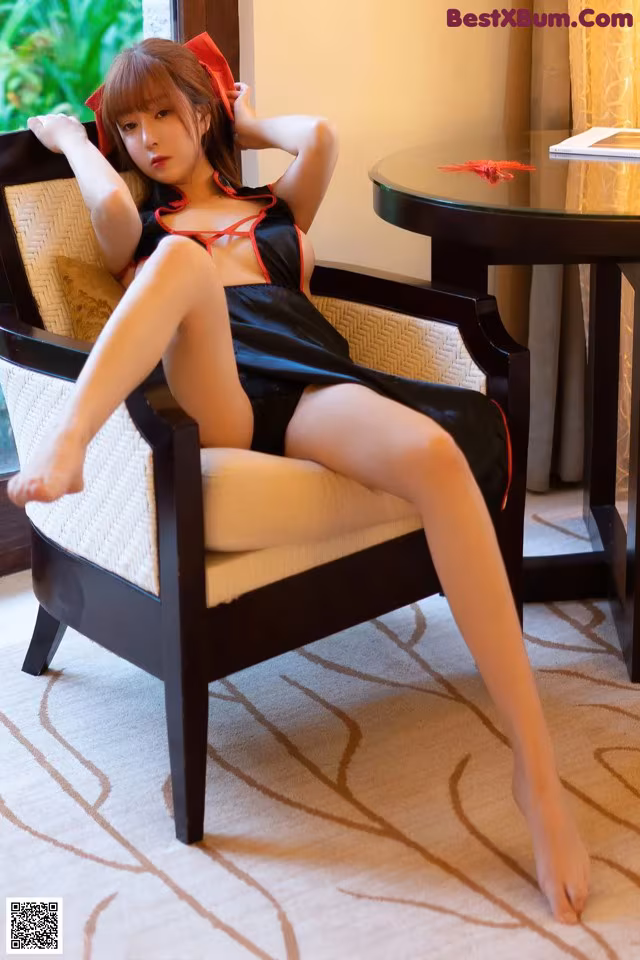A woman in a black and red lingerie sitting on a chair.