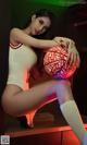 A woman sitting on a shelf holding a basketball.