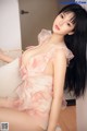 A woman in a pink dress sitting on a white couch.