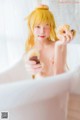 A woman in a bathtub holding a donut in her hand.