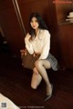 A woman in a white shirt and gray skirt posing for a picture.