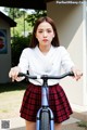 A young woman in a school uniform riding a bike.