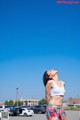 A woman standing in a parking lot with her eyes closed.