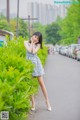 A woman in a blue dress standing on the side of a road.