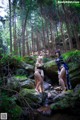 A couple of women standing next to each other near a stream.