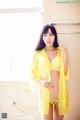 A woman in a yellow lingerie posing for the camera.