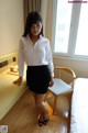 A woman in a white shirt and black skirt posing for a picture.